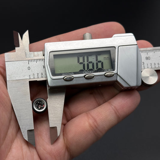Small gray toy wheel hub with hex lug opening and four circular details, shown with caliper