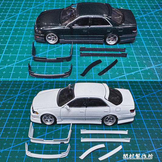 Unassembled sport body kit parts: white and black panels, bumpers and skirts on a mat