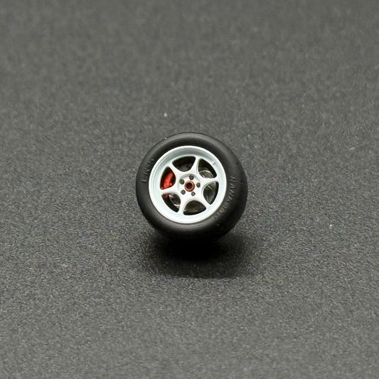 1/64 model wheel with silver multi-spoke rim and black tire, red details on hub