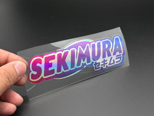 SEKIMURA Japan sticker held by hand, rainbow border and Japanese characters