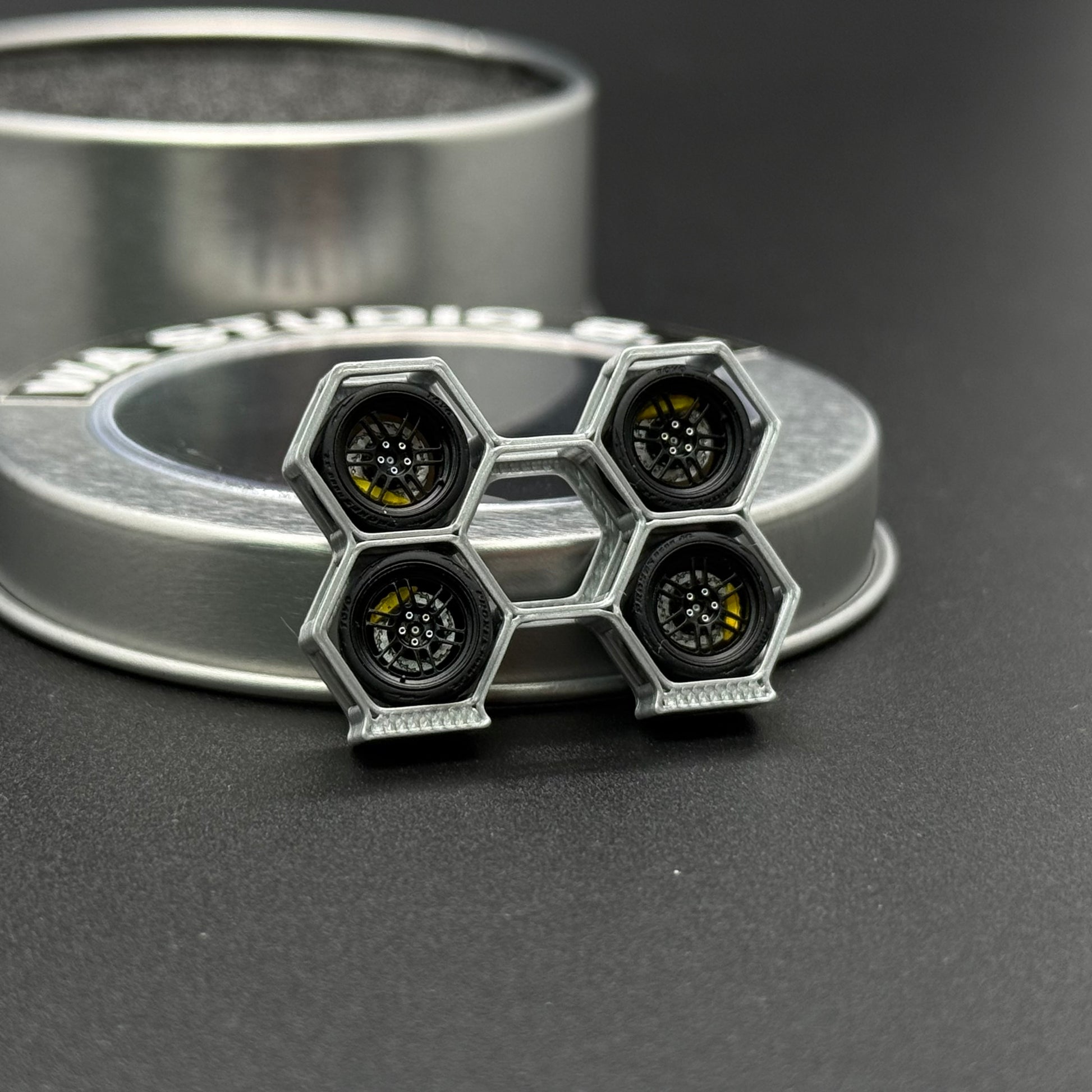 WA STUDIO 1/64 wheels, pair with hex-pattern black hubs and metallic rims, side view