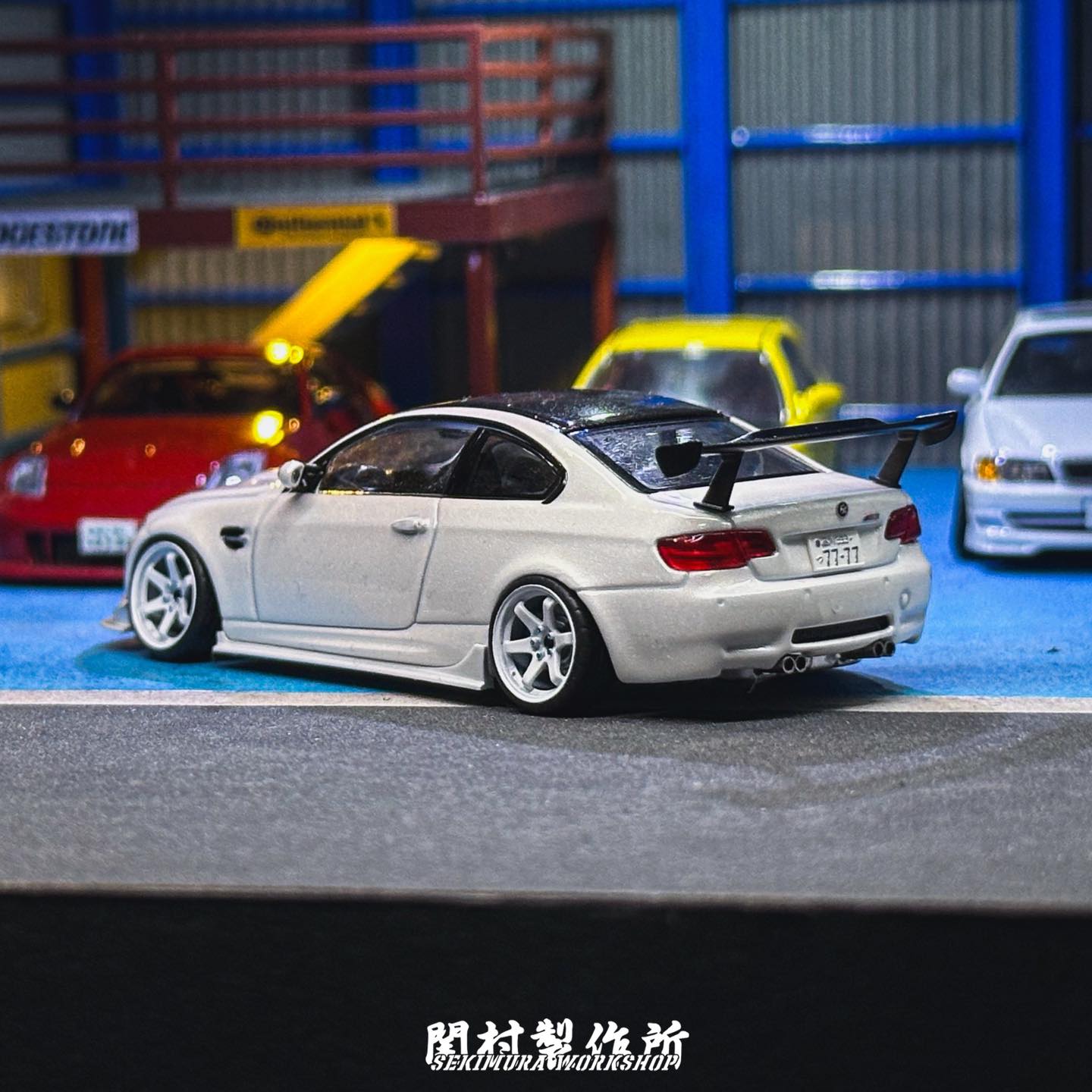 White assist-style bodykit on model coupe, rear bumper and deck spoiler