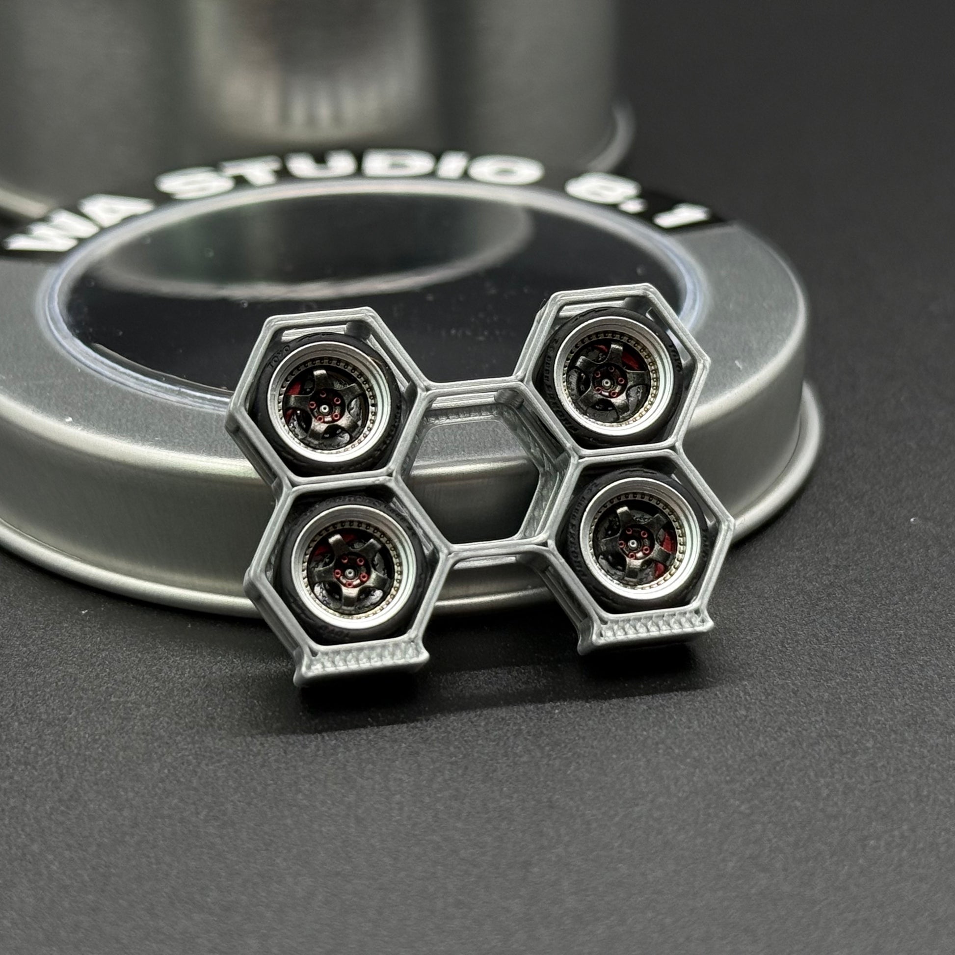 Toy wheel with four hex lug openings and four circular accents on a silver-gray rim