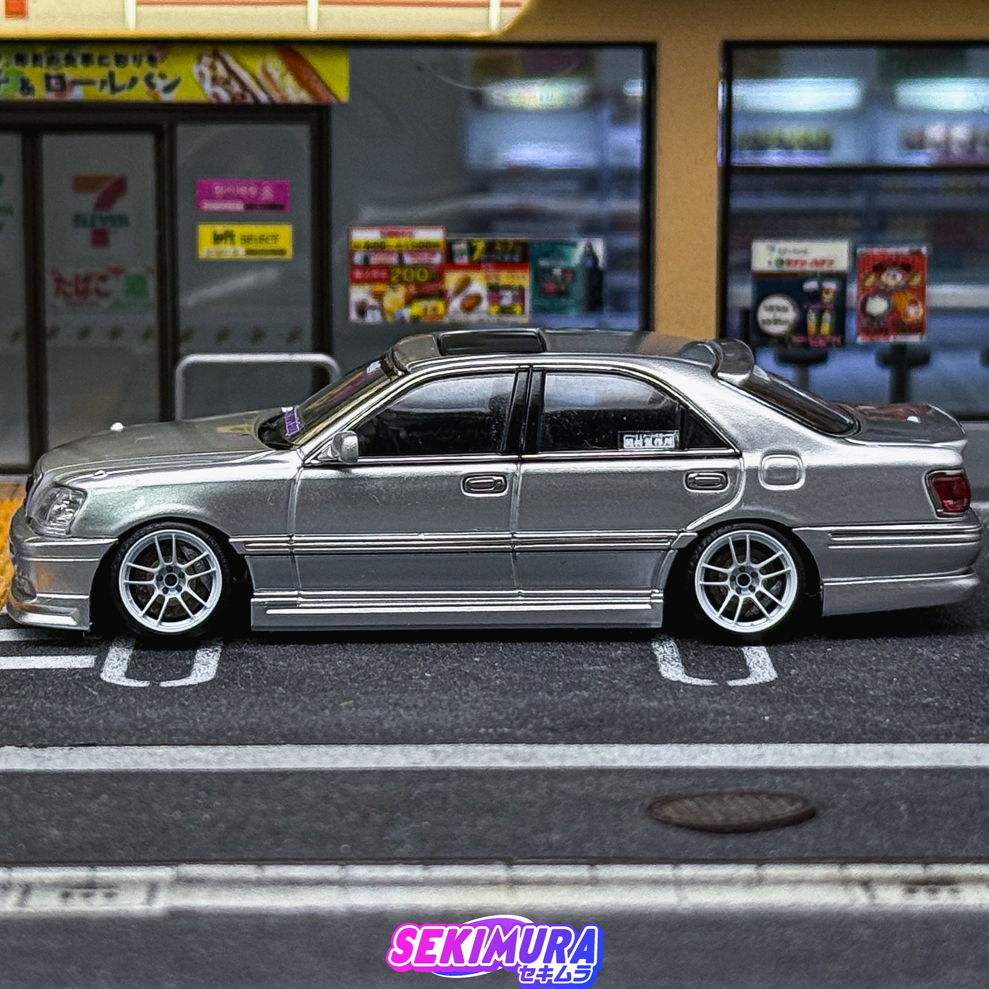 Silver die-cast-style sedan side profile with bodykit wheels and rear lip