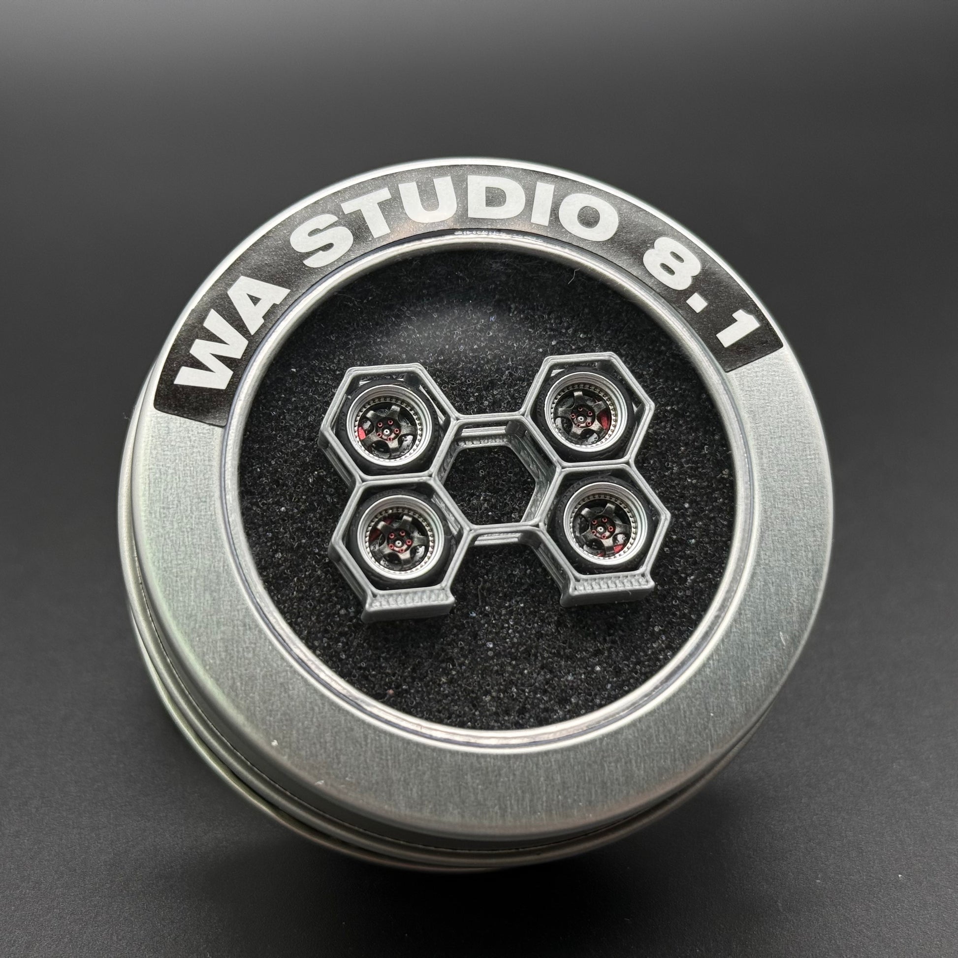 Steel-gray toy wheel with embossed ring text and four-lug hex hub with circular details