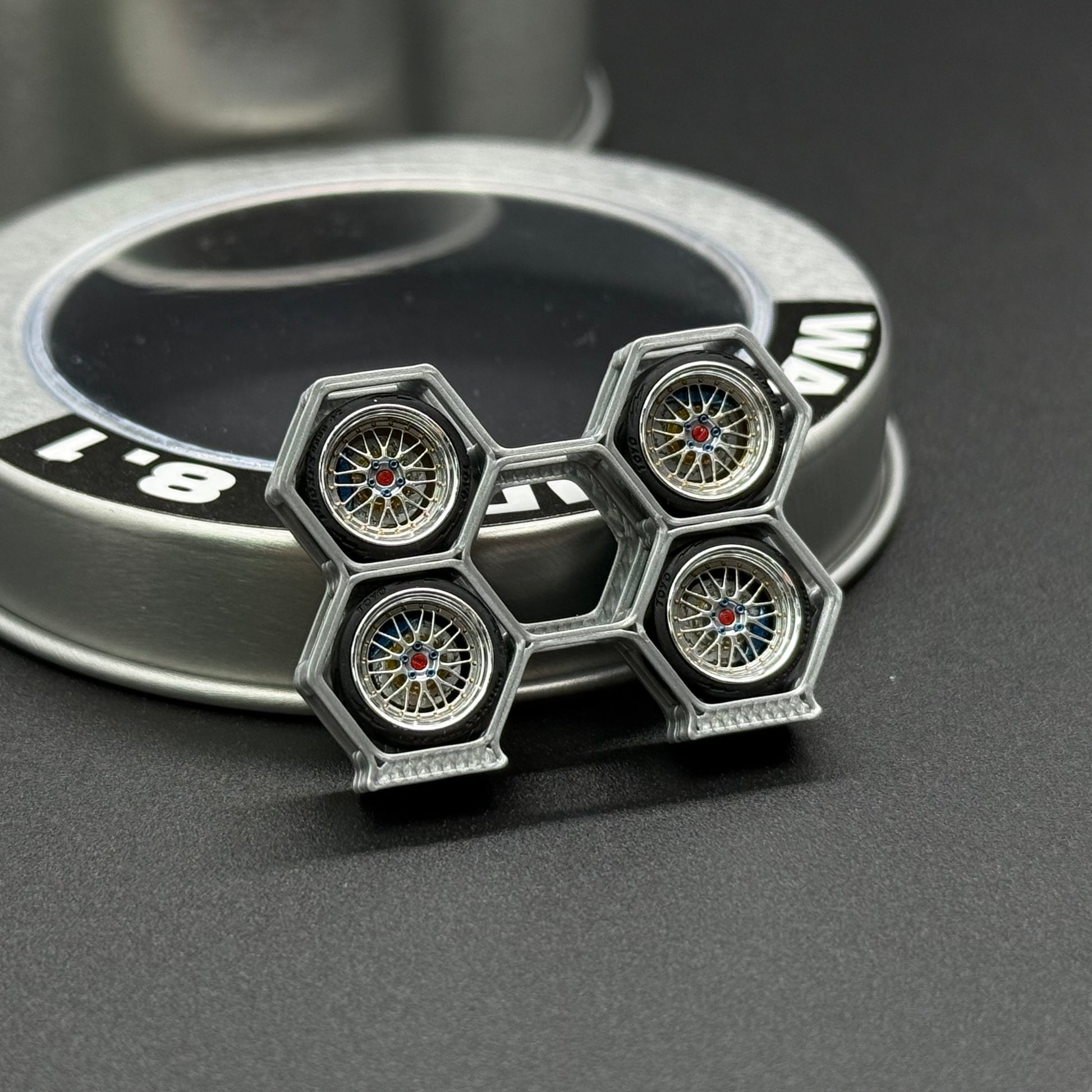 Four silver wheel rims with multicolor hubs, next to WA STUDIO wheel cap