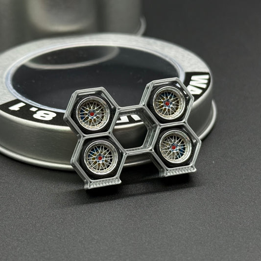 Four silver wheel rims with multicolor hubs, next to WA STUDIO wheel cap