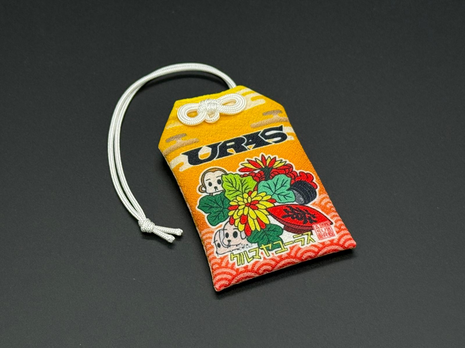 Traffic safety omamori charm pouch, orange and yellow with floral artwork and white cord