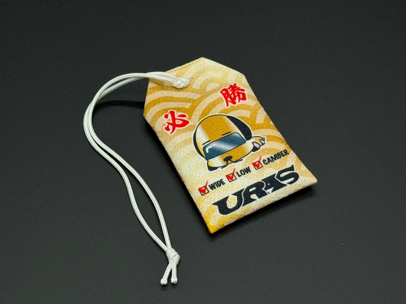 Traffic safety omamori charm pouch, yellow with car graphic and red text, white cord