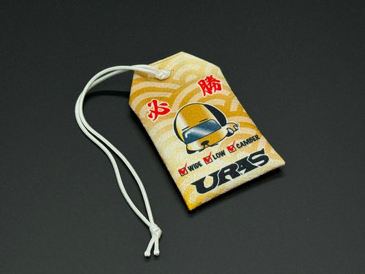 Traffic safety omamori charm pouch, yellow with car graphic and red text, white cord