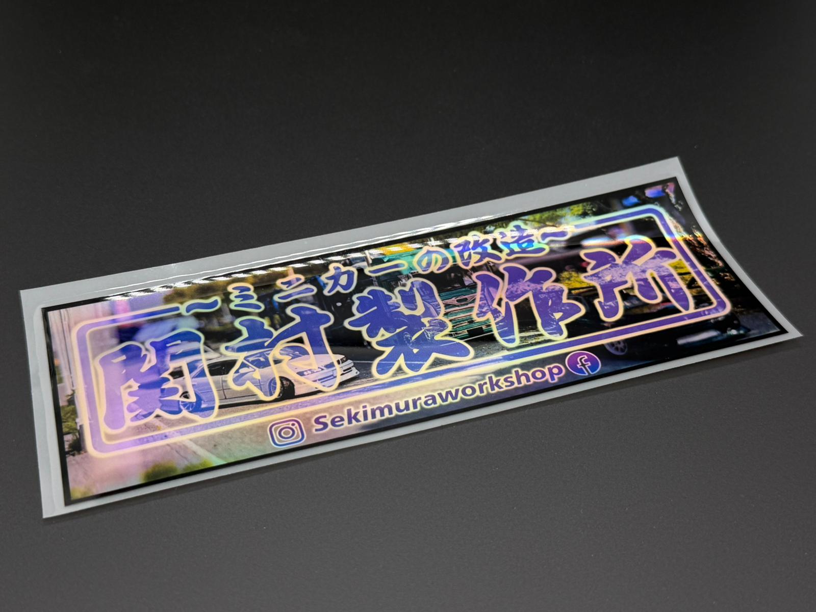 Holographic rectangular sticker with blue Japanese text and neon outline, white border