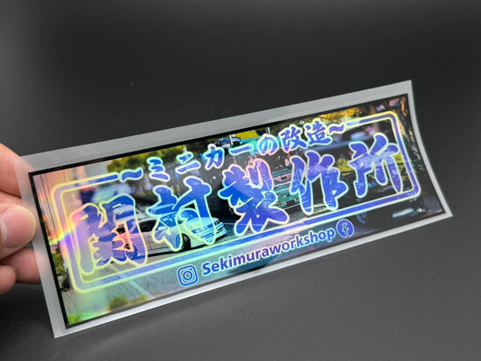 Holographic rectangular sticker with blue Japanese text and neon frame, with social handle
