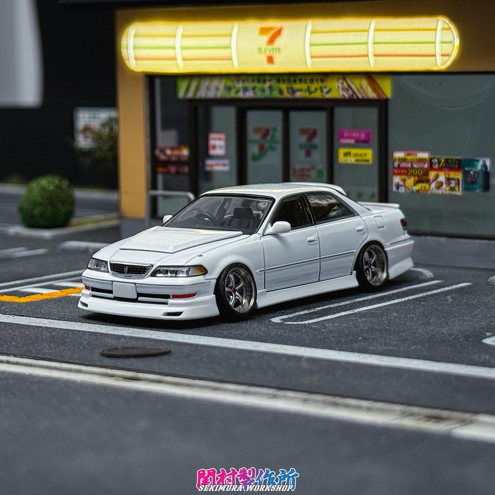 White JZX100 Mark2 model sedan with front bumper lip and chrome wheels, front view