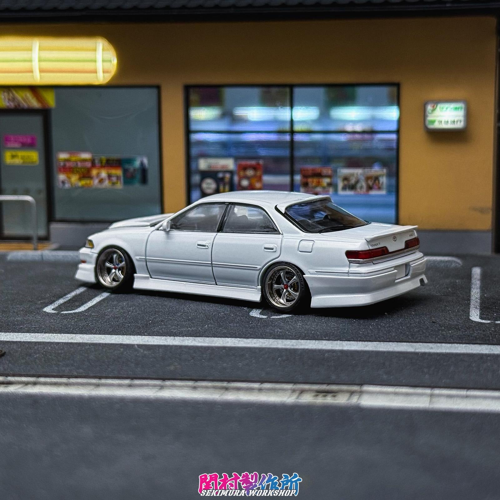 White JZX100 Mark2 model sedan with rear spoiler and upgraded wheels, side view