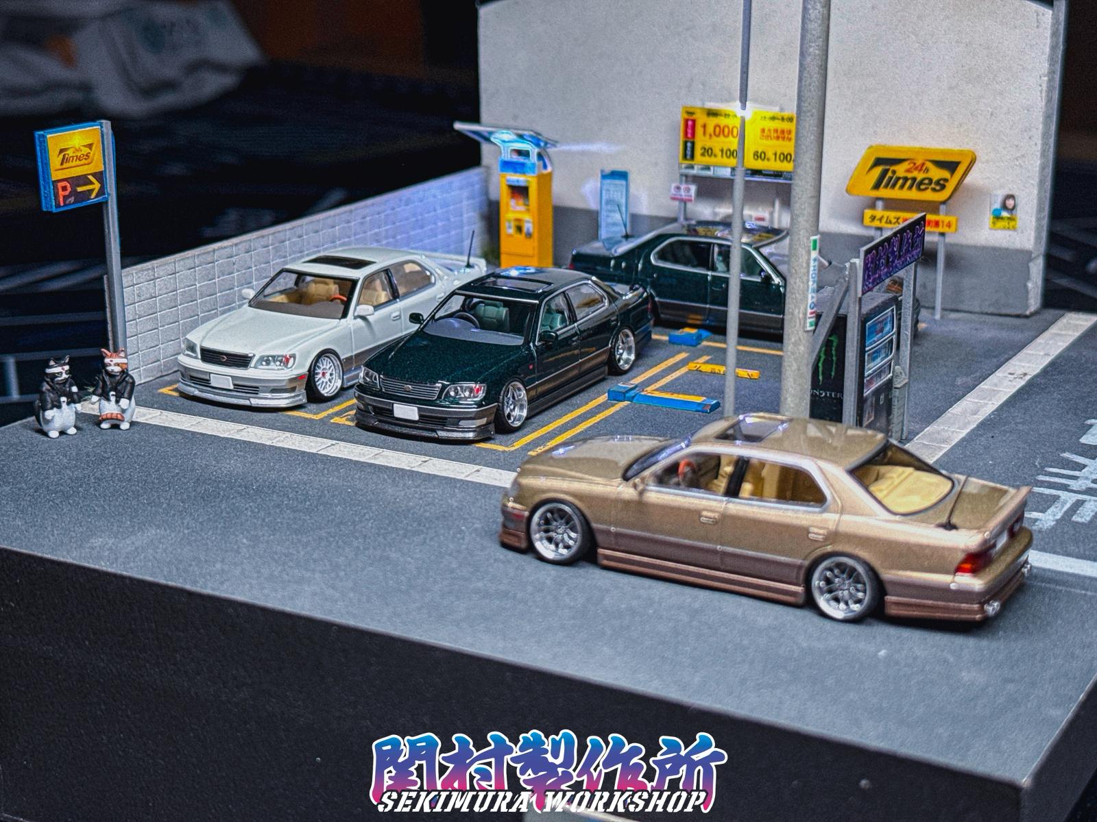Three die-cast cars parked at street gas station, featuring Wald-style body kits