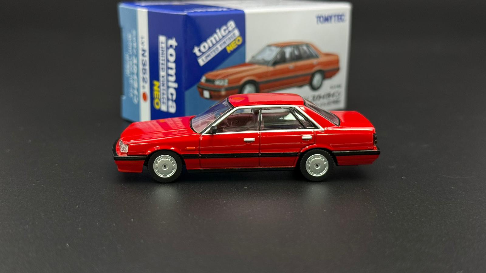 Red 1/64 scale 4-door sedan model car, side profile