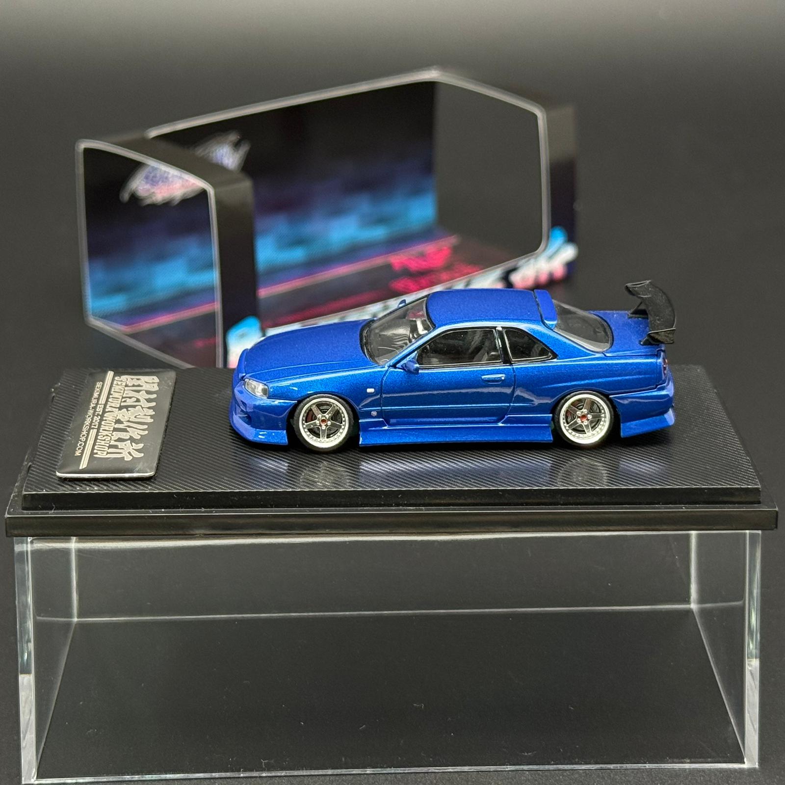 Blue 2-door die-cast car model side view on black display base