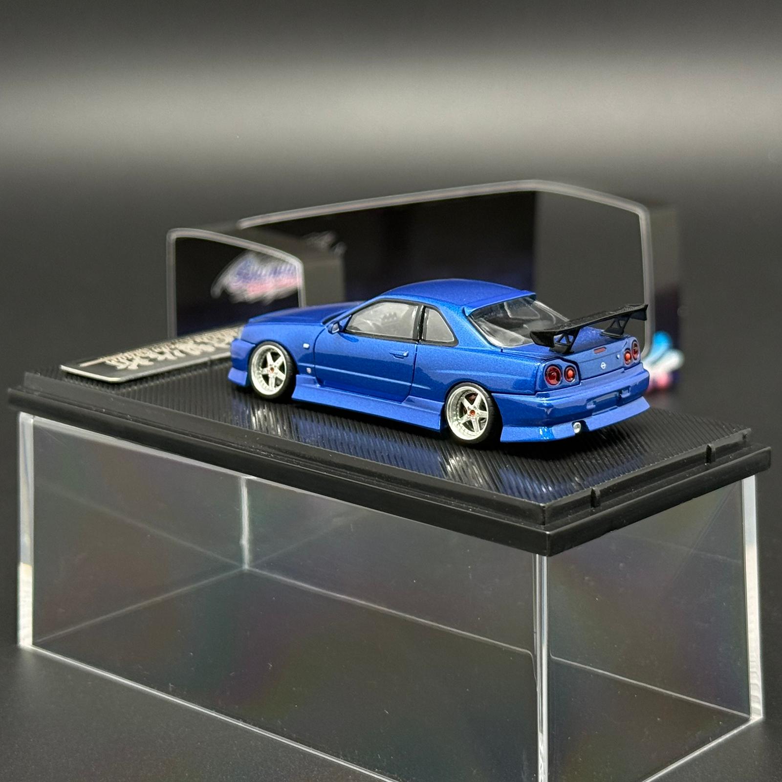 Blue 2-door die-cast car model rear 3/4 view on black display base