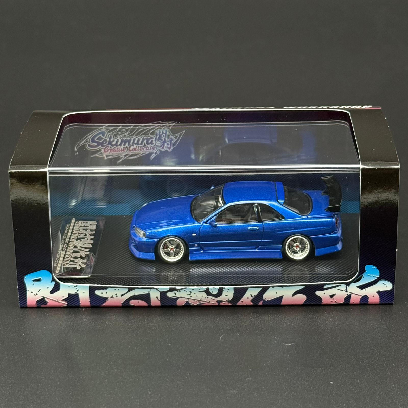 Blue 2-door die-cast car model on black display base inside clear case