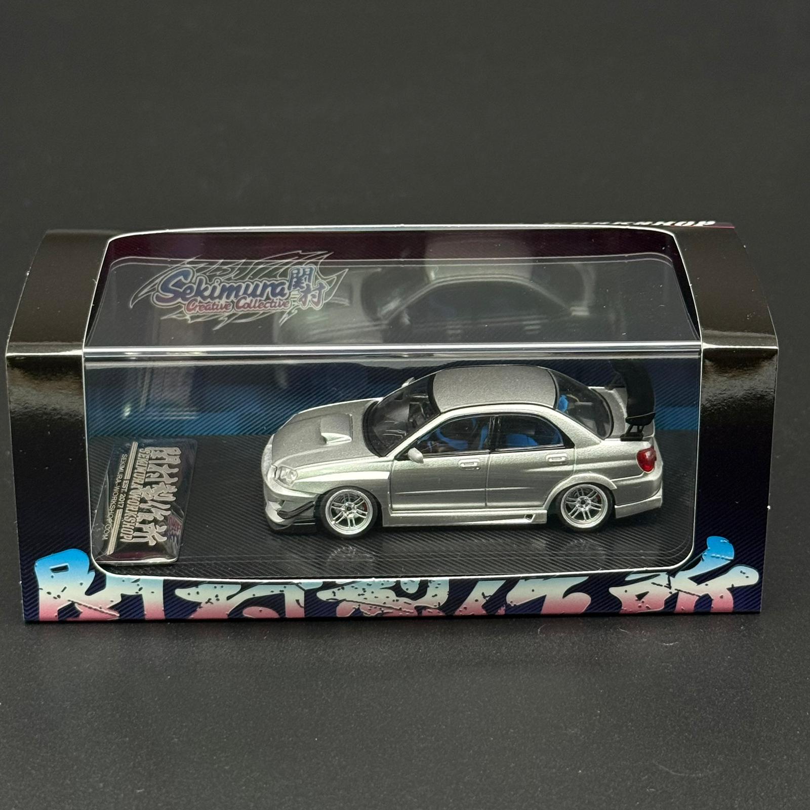 Silver 1/64 scale sports car model in display box, rear wing and white wheels