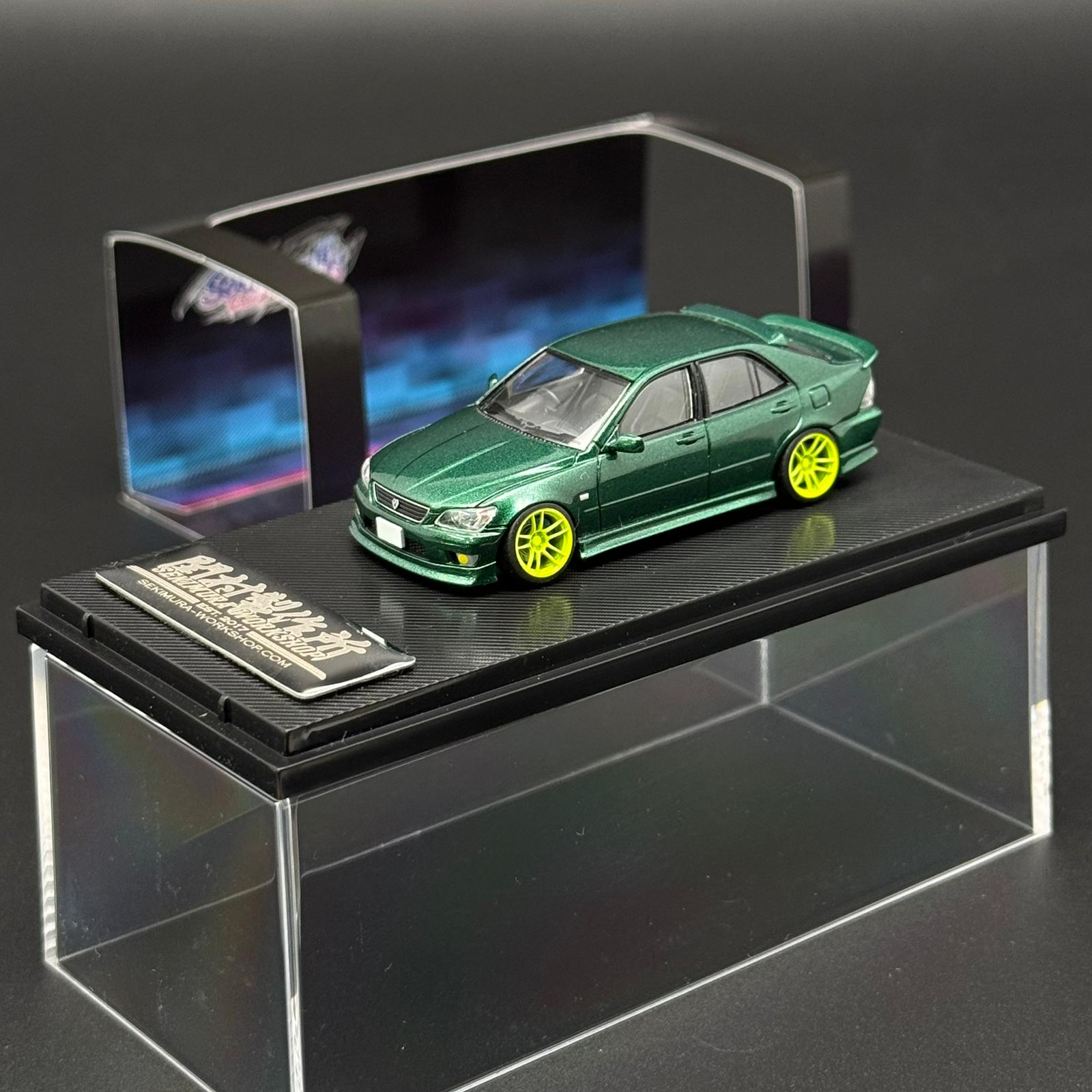 1/64 scale green die-cast car model with yellow wheels on black display base