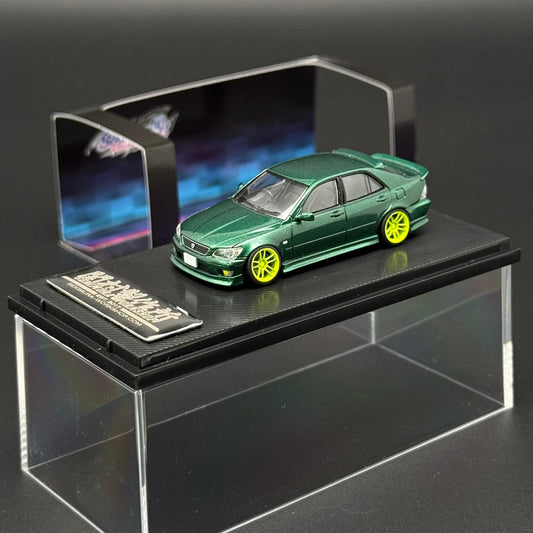 1/64 scale green die-cast car model with yellow wheels on black display base