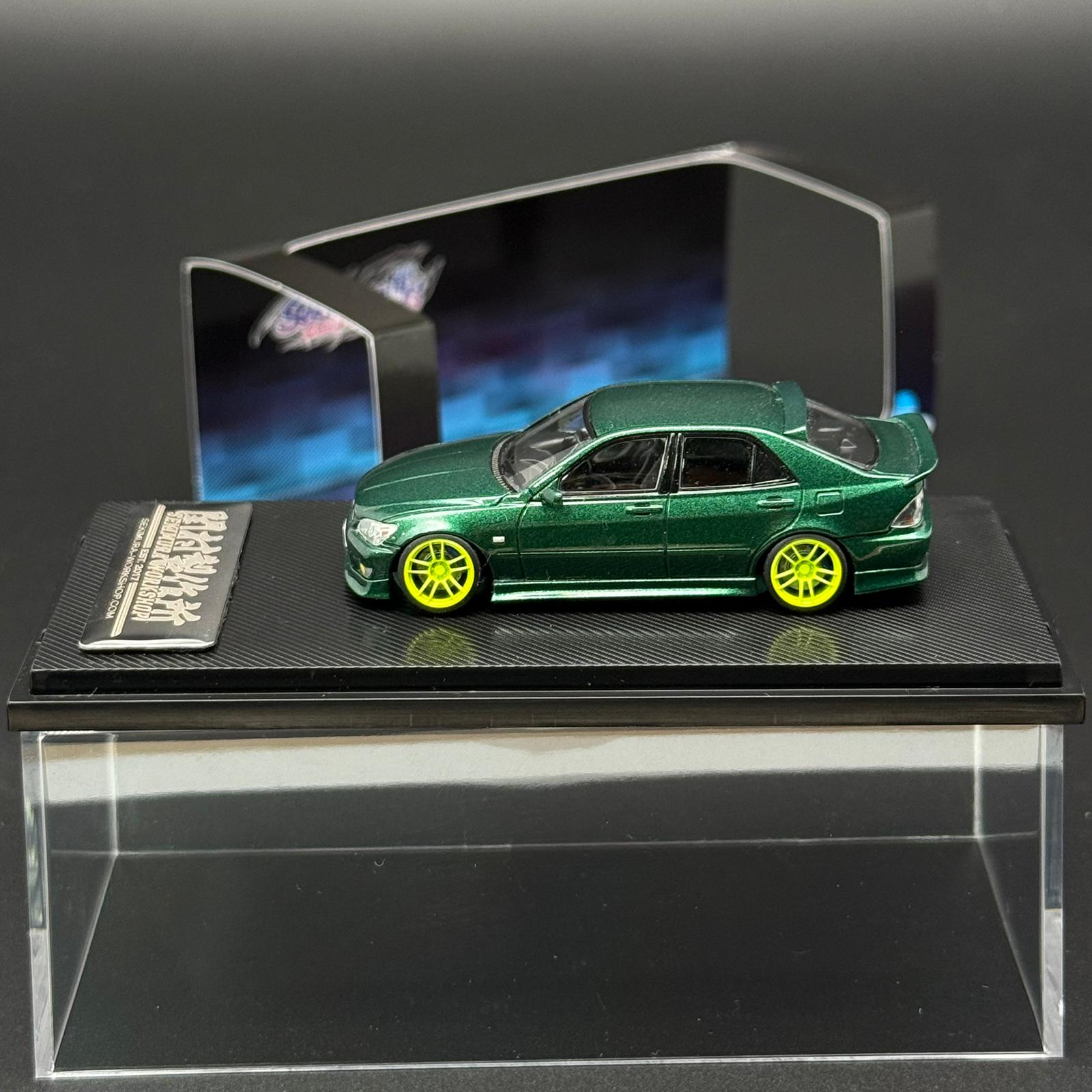 1/64 scale green die-cast car model with yellow wheels in clear display case
