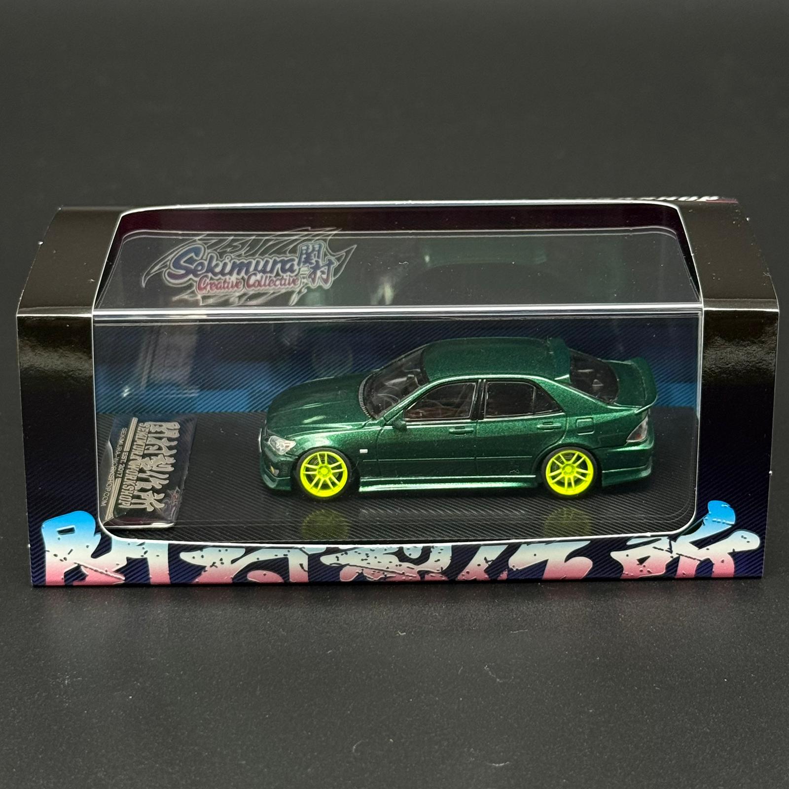 1/64 scale green die-cast car model with yellow wheels in retail display box
