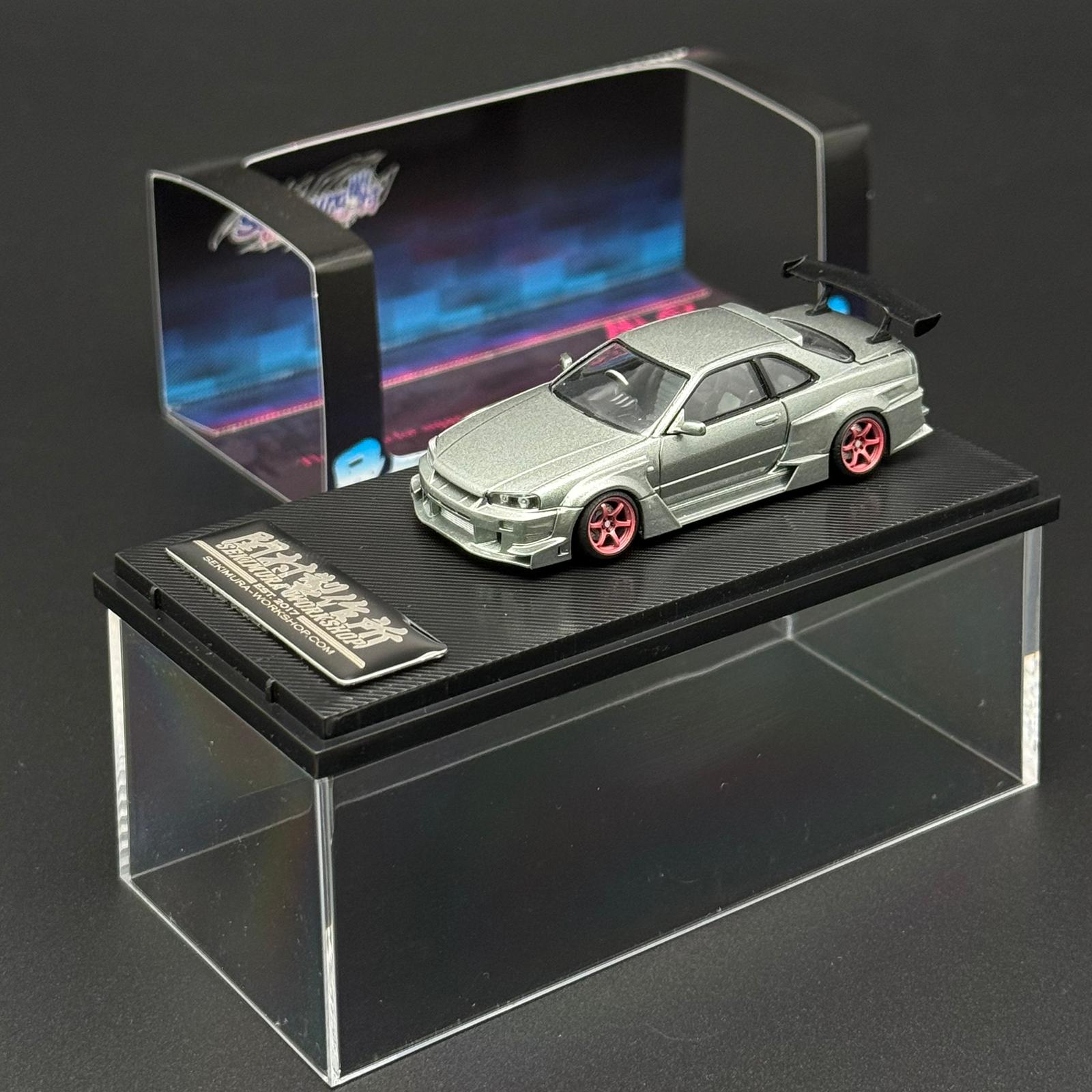 Light green scale model car with red rims on black base in clear display case