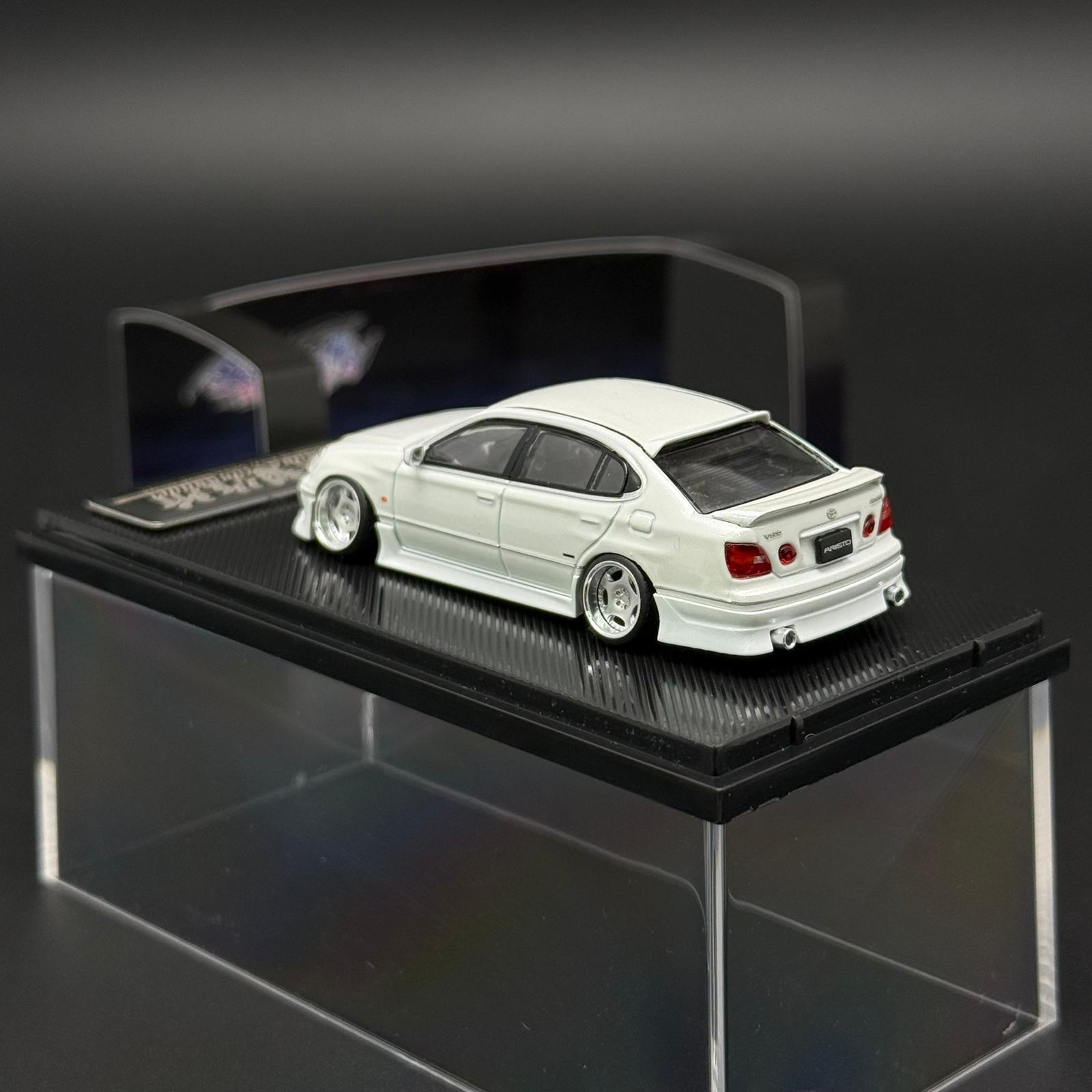 White 1/64 die-cast model coupe on clear display stand, rear three-quarter view