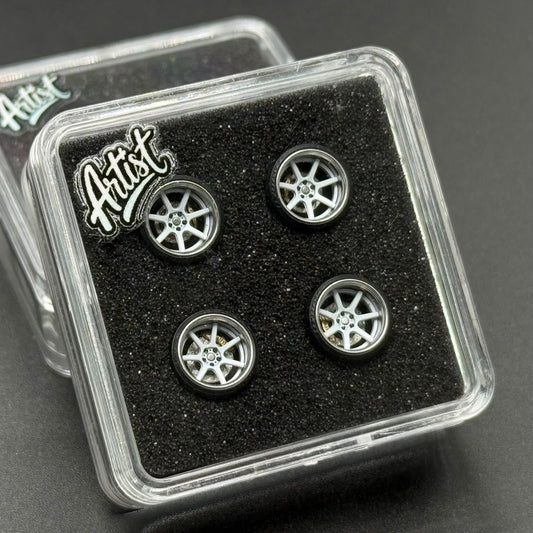 Four miniature silver wheels in clear plastic packaging with foam insert