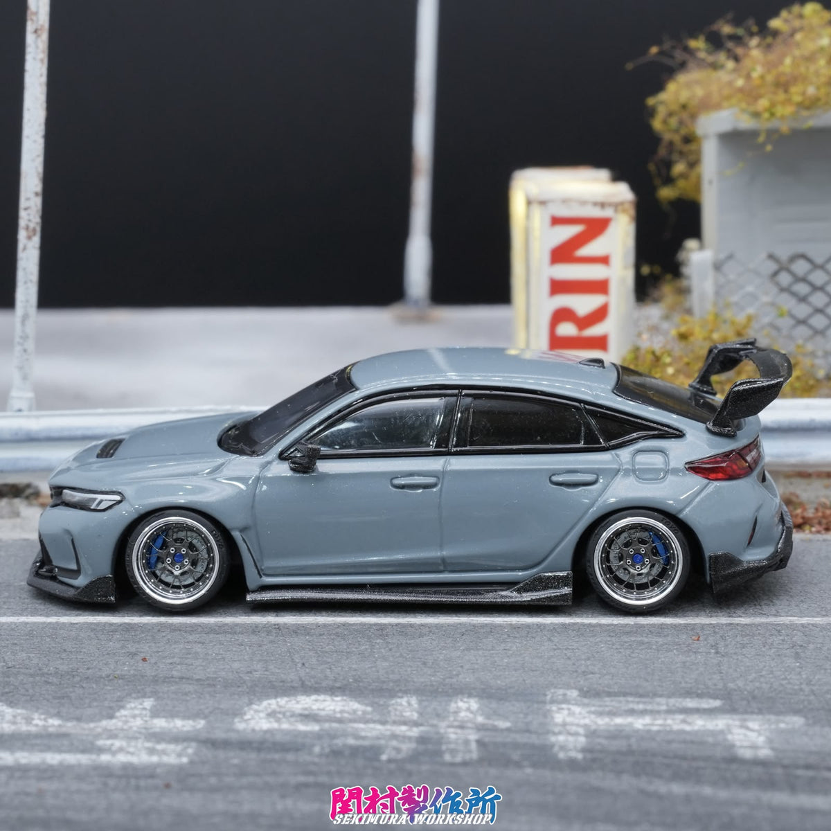 Light blue model car side view with body kit, rear wing, blue alloy wheels