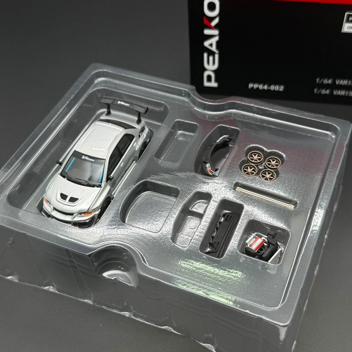 PEAKO 1/64 die-cast model car in clear blister tray with small accessory parts
