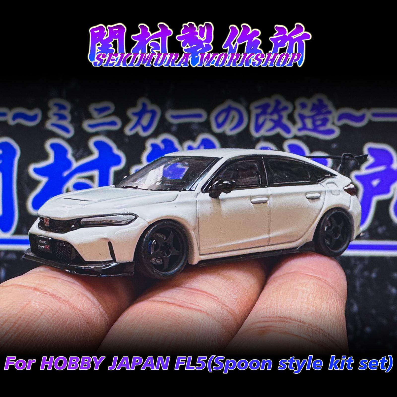 White sport car model on fingers, black wheels and front grille detail