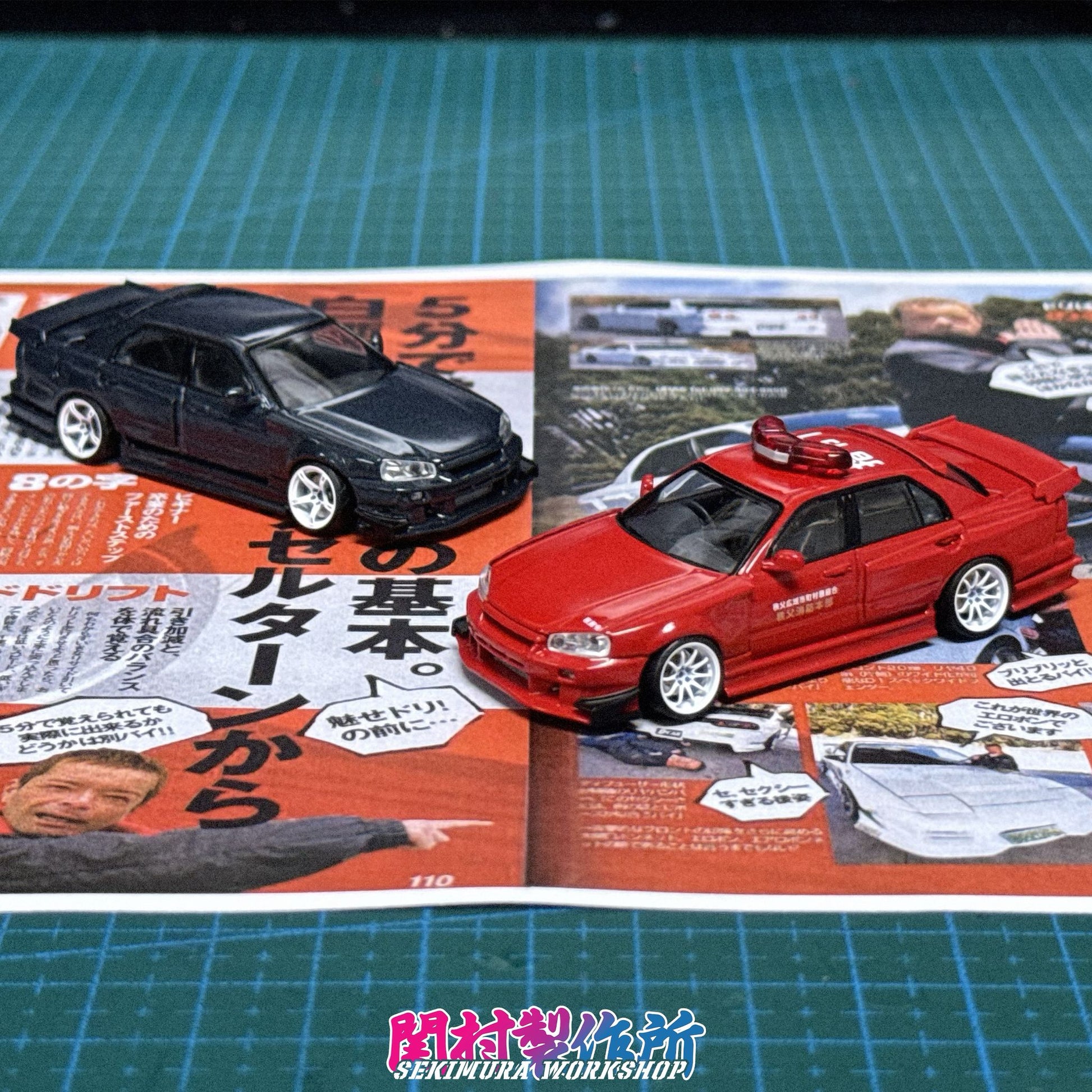Two die-cast car models, black and red, on display with bodykit features