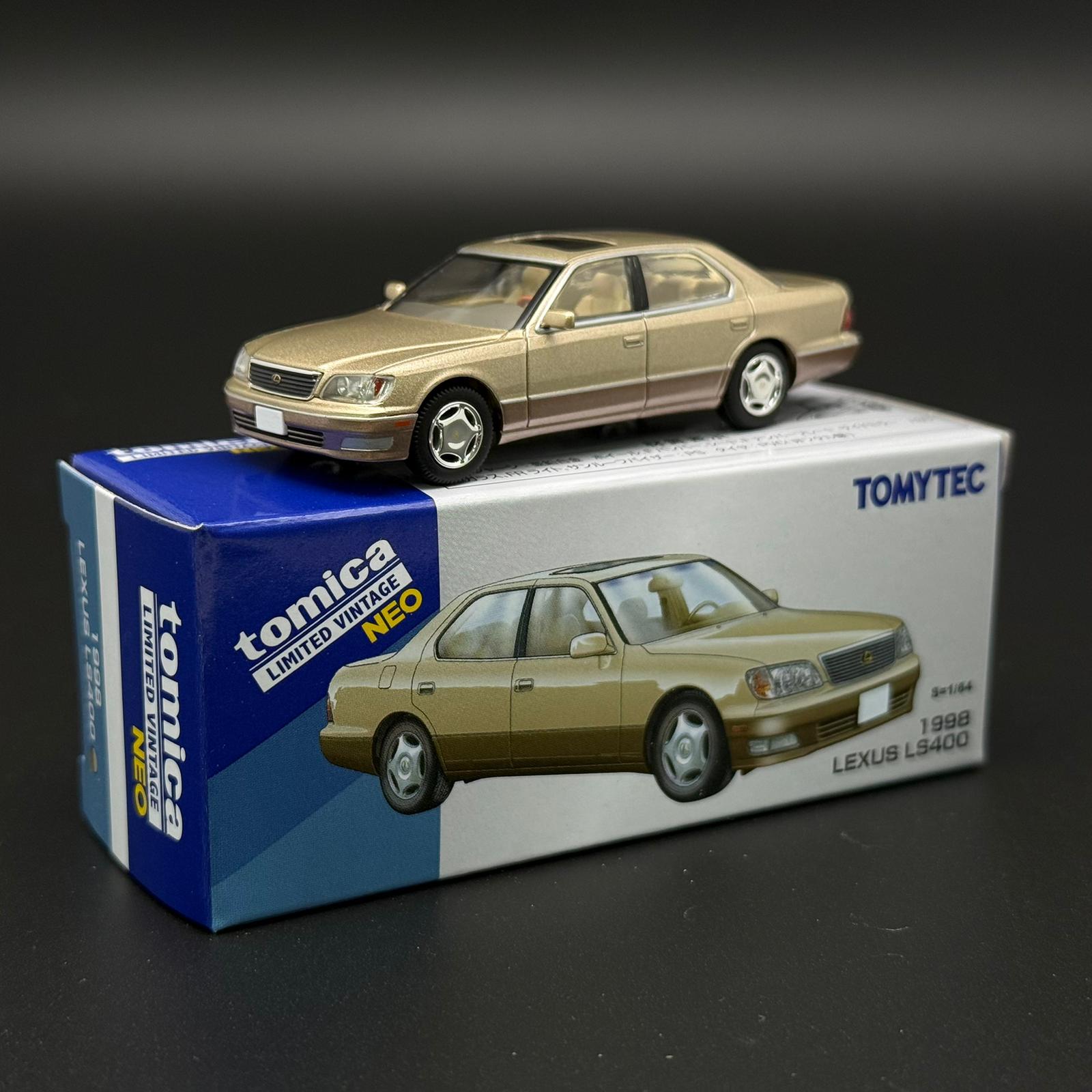 Gold two-door die-cast car model with front grille and silver wheels on display box