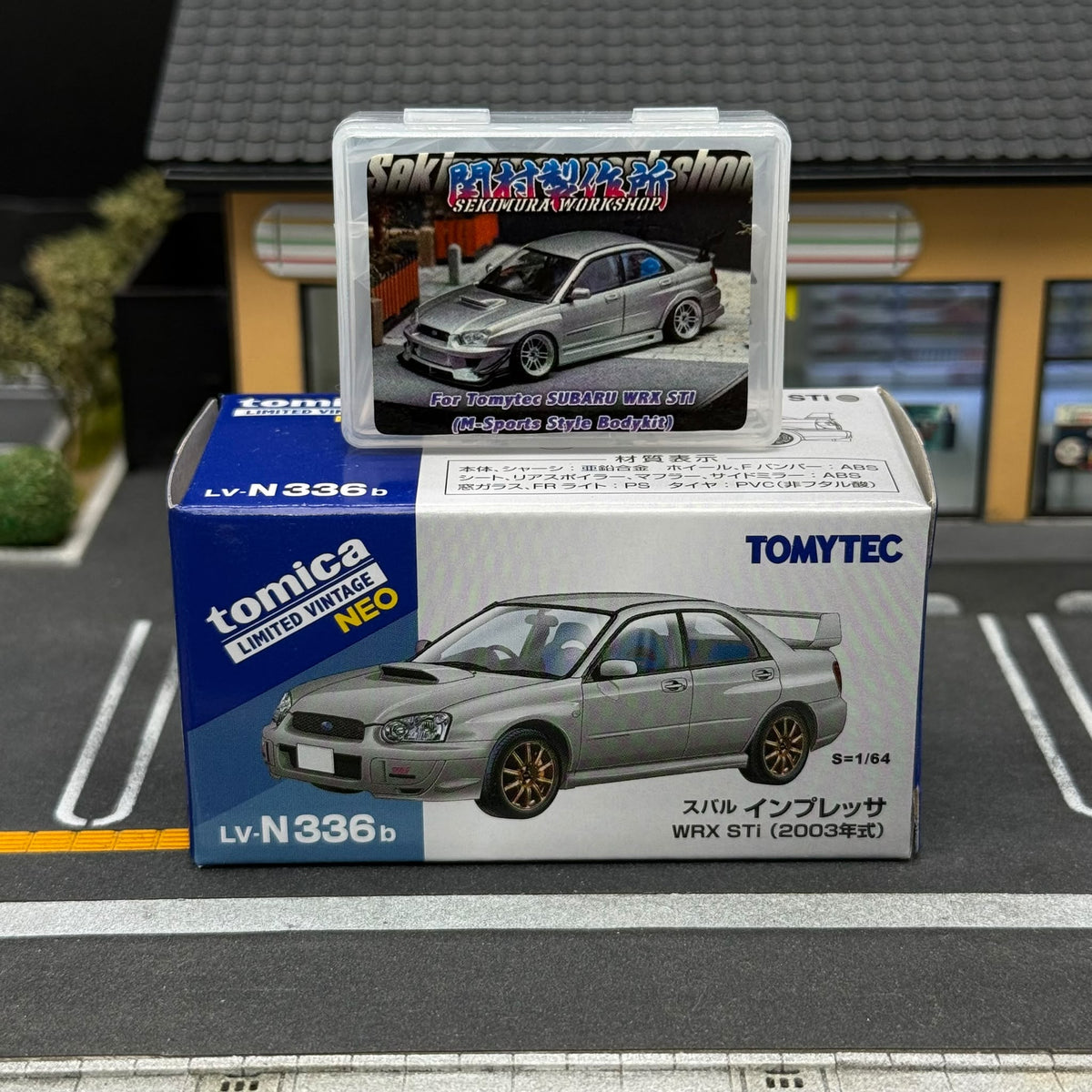 Silver Subaru WRX STI miniature and body kit package beside a Tomytec model car box